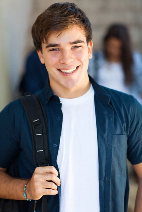 Un retrato escolar de un estudiante de secundaria masculino feliz sonriendo en un pasillo de la escuela: consejos para retratos escolares de calidad