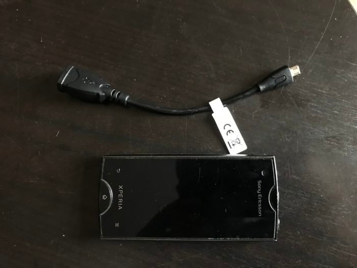 Fotografía cenital de un Sony Xperia Ray y un cable microUSB OTG en una mesa negra