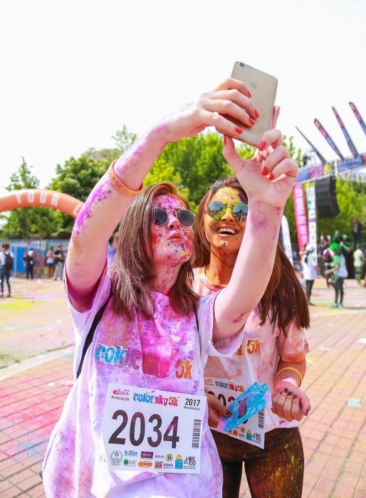 Chicas cubiertas con polvos de colores posando para un selfie al aire libre