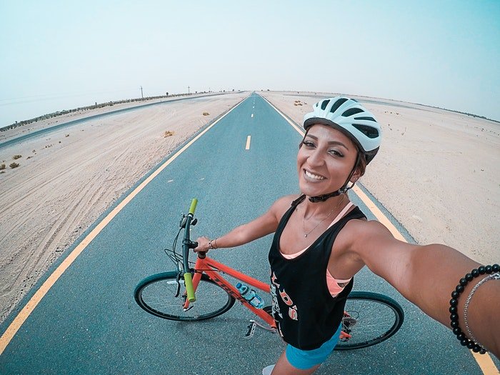 Una chica tomando un selfie mientras anda en bicicleta.
