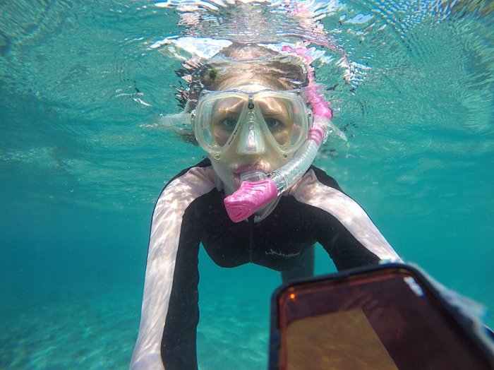 Una chica de snorkel tomando un selfie bajo el agua.