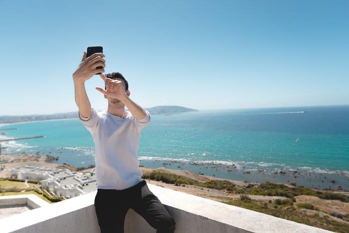 Un joven tomando un selfie frente al mar.