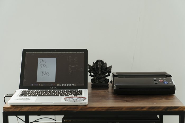 Una computadora portátil y una impresora en un escritorio de madera