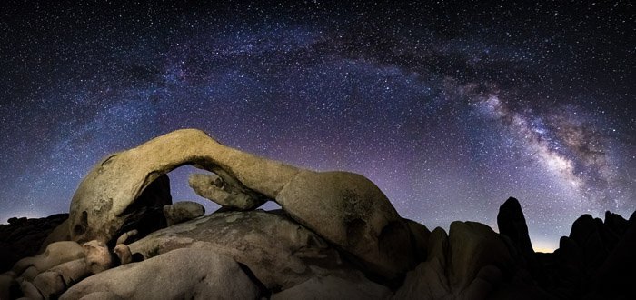 Toma de astrofotografía de fotograma completo de una roca en el primer plano de un impresionante cielo nocturno lleno de comienzo.  Tomada con lente rokinon de 14 mm a