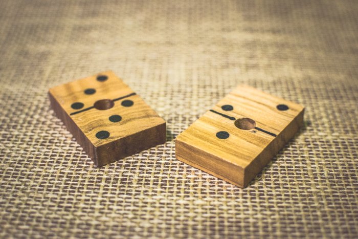 Cerca de dos fichas de dominó de madera sobre una mesa marrón