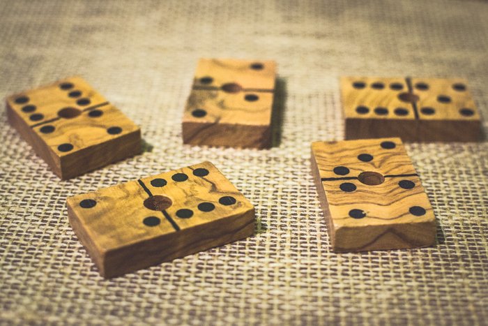 Cerca de cinco fichas de dominó de madera sobre una mesa marrón