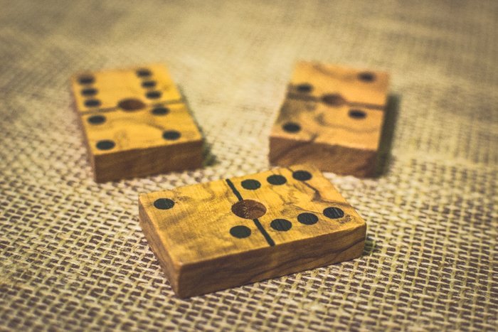 Cerca de tres fichas de dominó de madera sobre una mesa marrón utilizando la regla de composición de probabilidades