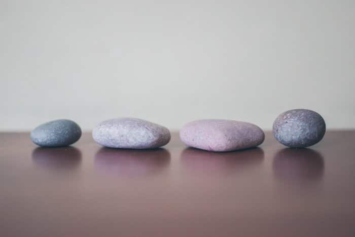 Cuatro piedras grises alineadas sobre una superficie de madera