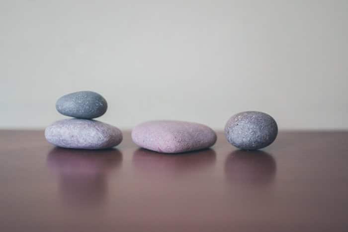 Cuatro piedras grises sobre una superficie de madera, dos apiladas, utilizando la regla de composición de probabilidades