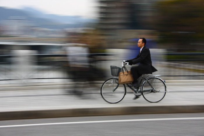Un hombre en bicicleta en un paisaje urbano con motio0n fondo borroso - regla de la fotografía espacial
