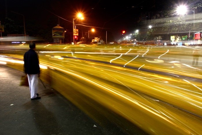 Una persona que camina por una calle muy transitada por la noche usando la configuración de la cámara de larga exposición para la fotografía de la calle
