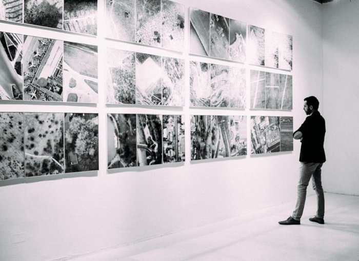 Imagen en blanco y negro de un hombre viendo imágenes en una galería.