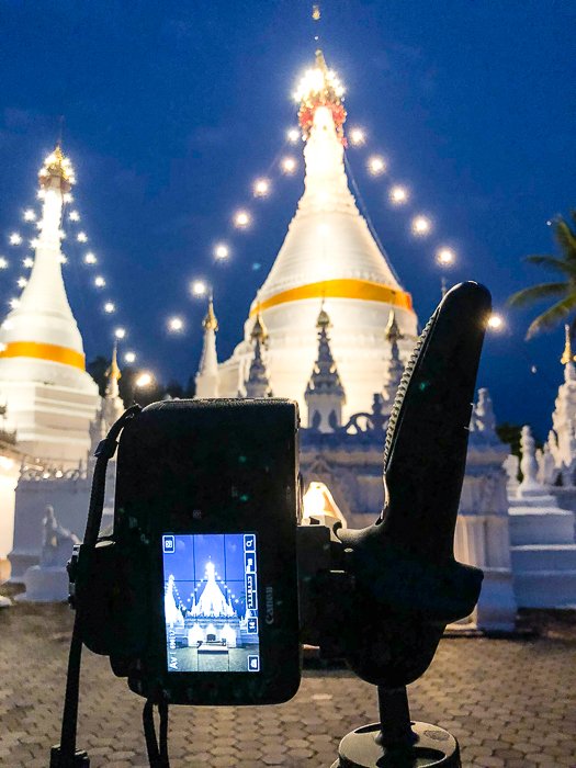 Una cámara réflex digital en un trípode disparando una fotografía estelar sobre un edificio por la noche