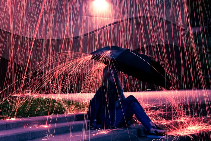 una niña sosteniendo un paraguas bajo el efecto de lluvia creado por la fotografía de lana de acero