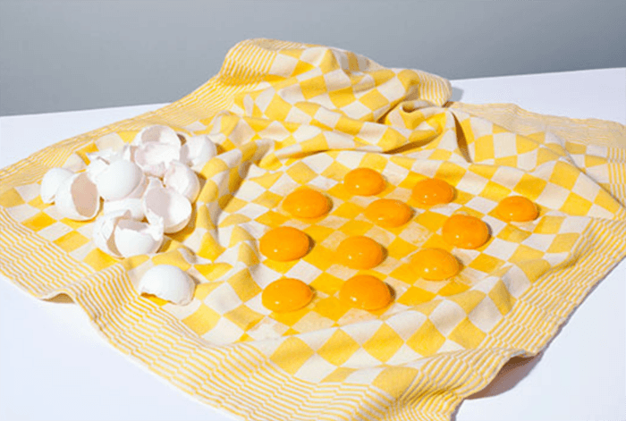 Foto de bodegón moderno de yemas de huevo colocadas sobre un trozo de tela que se asemeja a un tablero de ajedrez