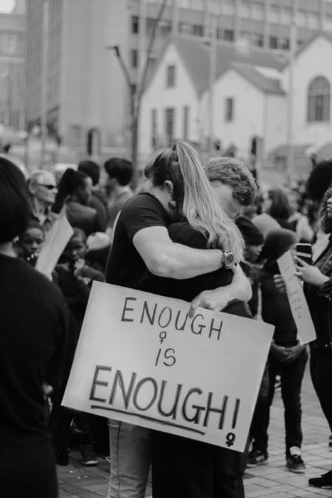 Imagen en blanco y negro de dos personas abrazándose durante una protesta