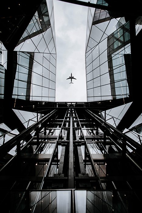 Interesante composición de un avión enmarcado por un edificio de vidrio de varias capas