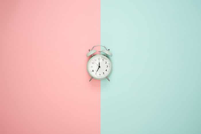Una imagen de producto peculiar de un reloj despertador que demuestra simetría en la fotografía debido a la composición central y al fondo de color dividido