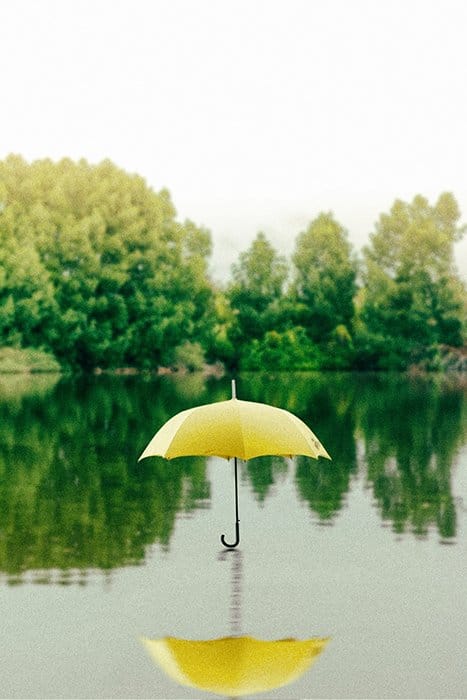 Saffu foto de un paraguas amarillo flotando sobre un lago - fotografía surrealista