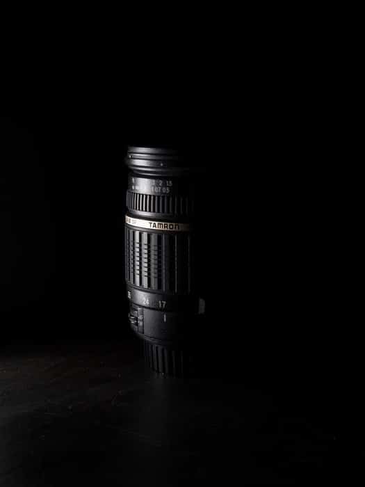 Foto oscura de una lente Tamron que resalta las abreviaturas de la lente Tamron