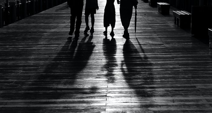 imagen en blanco y negro de cuatro personas de cintura para abajo y con sombras