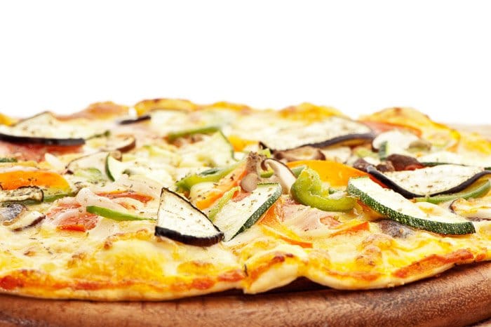 Primer plano de una pizza vegetariana recién hecha con una caja de luz directamente detrás del sujeto.