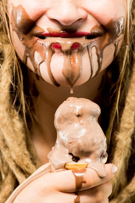 Un retrato en primer plano de una modelo femenina comiendo helado de chocolate shot con iluminación de caja de luz