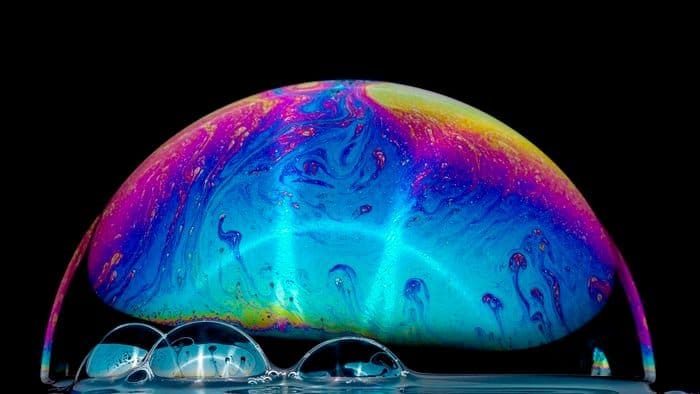 Fotografía macro de una pompa de jabón con los colores del arco iris