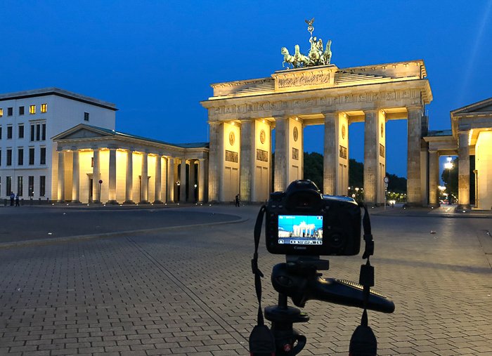 Una cámara DSLR en un trípode fotografiando la Puerta de Brandenburgo en Berlín por la noche
