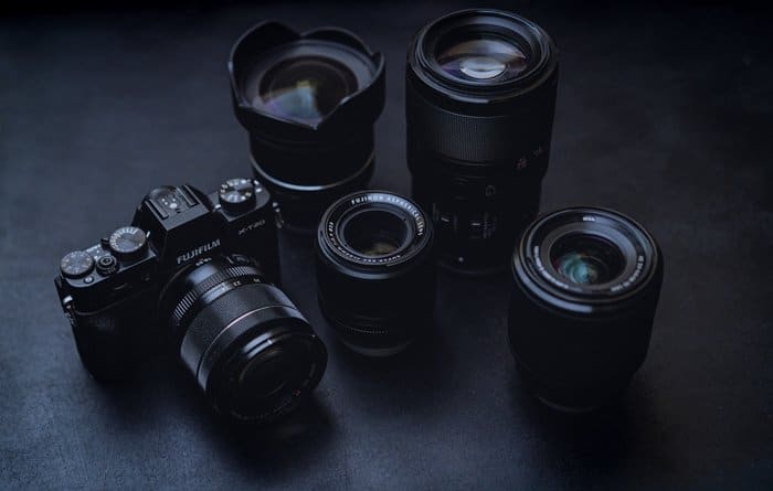 una cámara fujifilm con 4 tipos de lentes descansando sobre una superficie negra