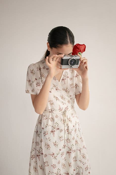 niña con vestido floral tomando una foto con una cámara de película