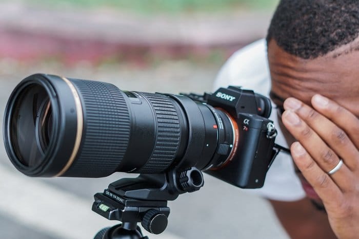 un fotógrafo mirando a través de una Sony dSLR con una lente Tamron