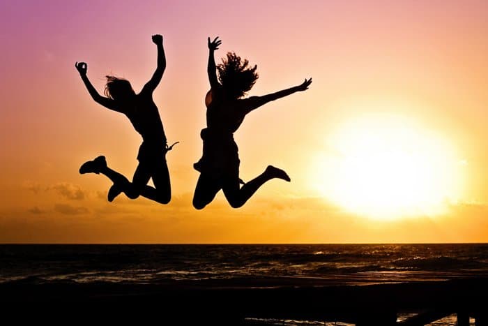La silueta de dos niñas saltando sobre el mar al atardecer