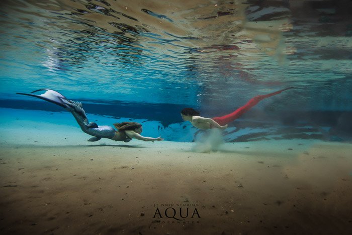 Una fotografía subacuática publicitaria de dos sirenas.