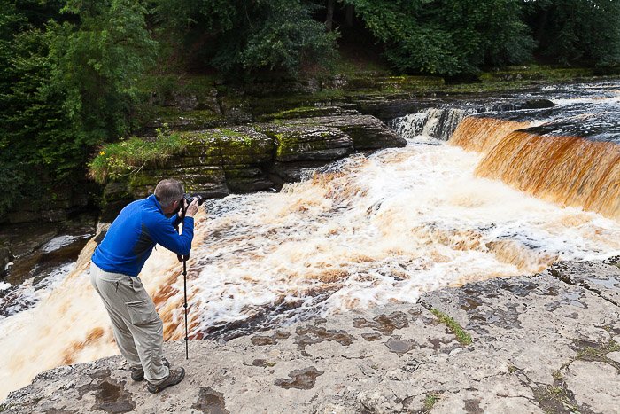 Un fotógrafo tomando una foto de una cascada: vende fotos en línea