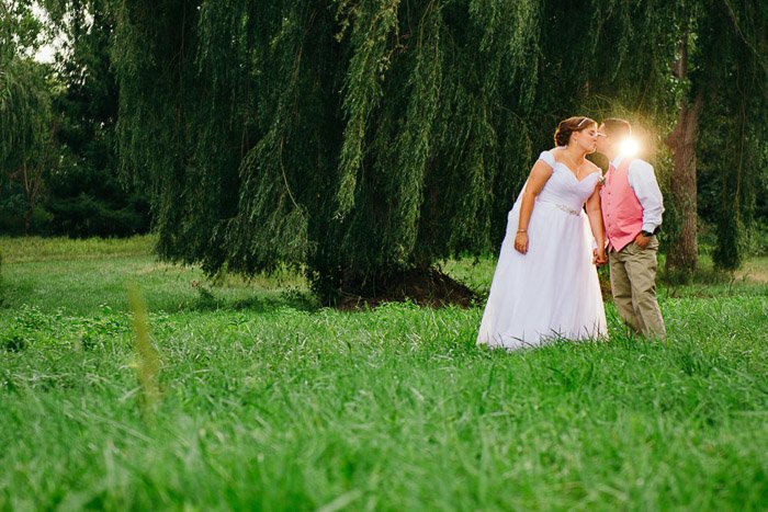 Una pareja de recién casados ​​besándose al aire libre, rodada con iluminación de flash Speedlight