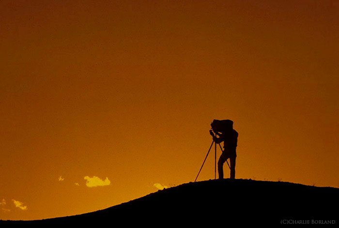 Una silueta de un fotógrafo de aventuras en solitario contra un cielo al atardecer