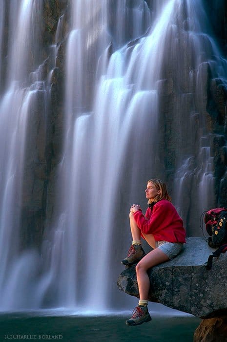Una fotógrafa de aventuras descansando sobre una roca en Rainbow Falls, California