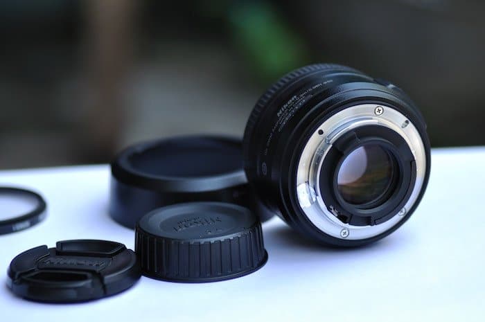 Una lente de cámara apoyada sobre una superficie blanca con diferentes tapas de lentes.