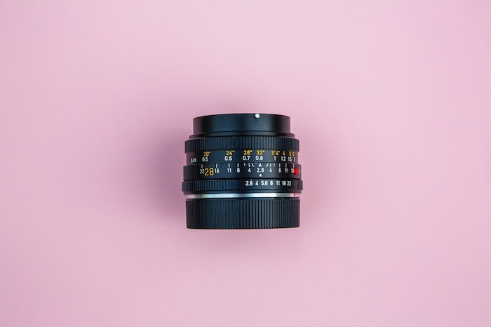 Fotografía cenital de la lente de una cámara sobre fondo rosa: la mejor lente para la fotografía de productos