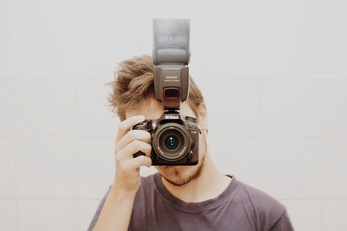 una foto de un fotógrafo tomando una foto con su cámara Nikon y flash