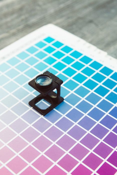 Una lupa apoyada sobre una cuadrícula de colores para papel de impresión fotográfica