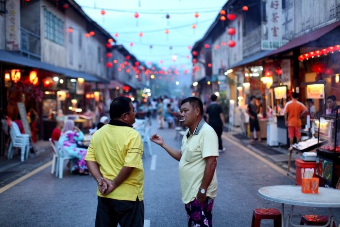 Fotografía documental de dos hombres charlando en una calle concurrida