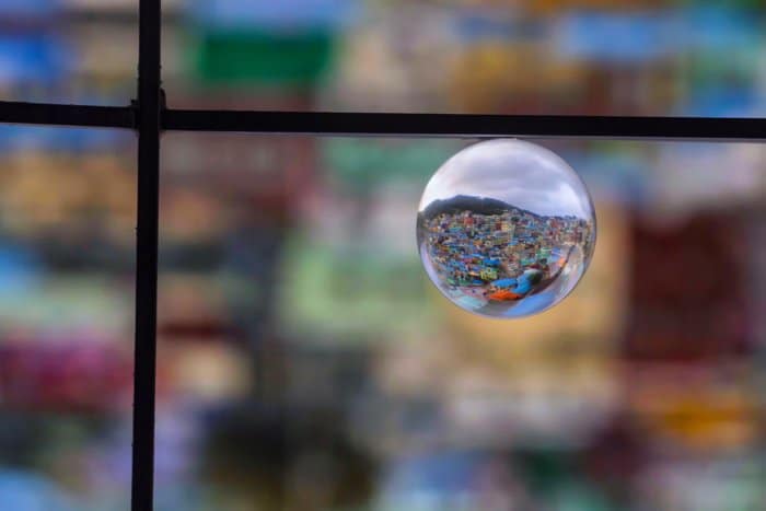una bola de cristal en el marco de una ventana que refleja un paisaje urbano en expansión