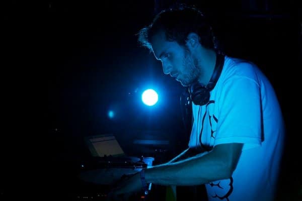 Foto de un DJ en luz azul mirando su equipo