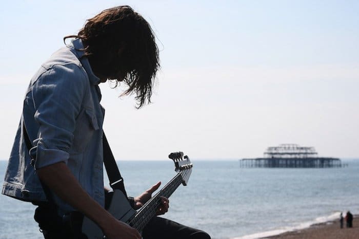 Un hombre tocando la guitarra junto al mar, filmado sin centrarse en el equilibrio en la fotografía