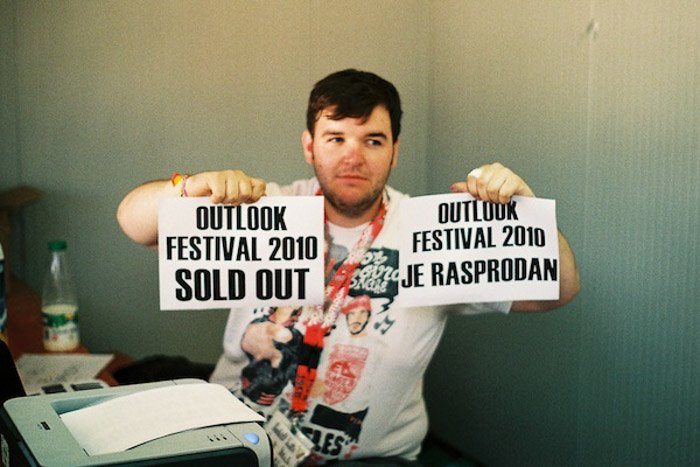 Un hombre sosteniendo dos carteles impresos que anuncian un festival está agotado - balance de fotografía 