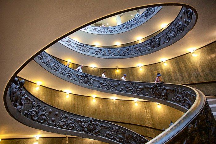 Personas caminando por una escalera de caracol en el interior de un edificio impresionante