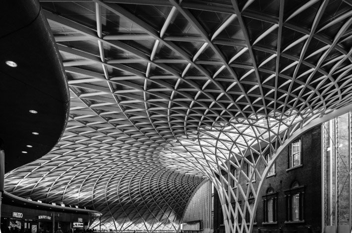 foto en blanco y negro del techo de la estación de tren de King's Cross London