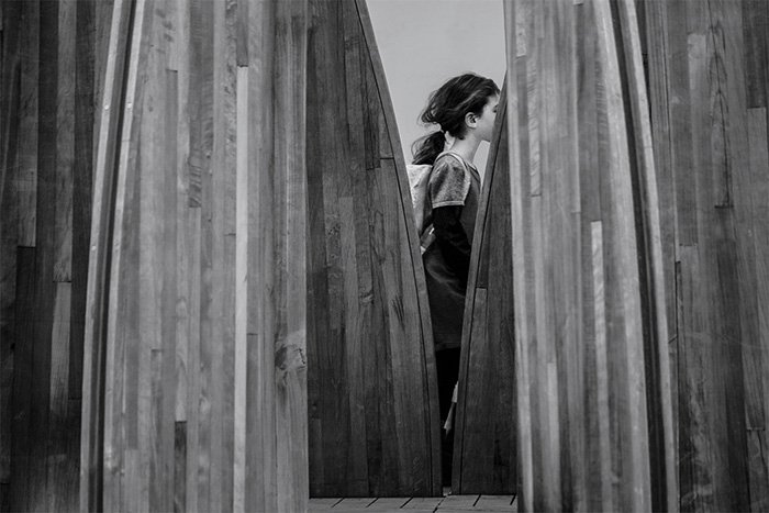 Fotografía en blanco y negro de una niña caminando entre unas tablas de madera